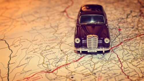 Hit the road - Travel concept with vintage miniature car on road map